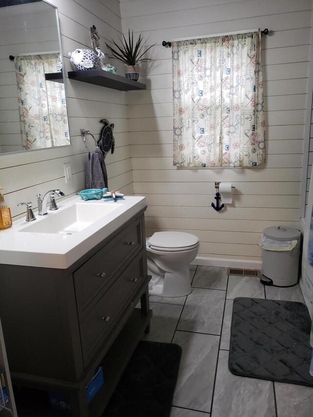 bathroom with wooden walls, vanity, and toilet