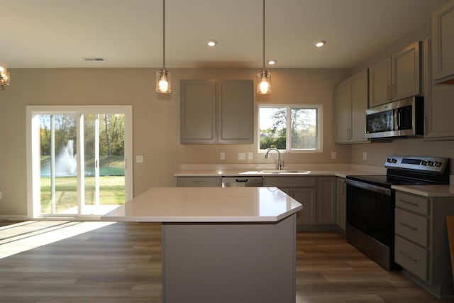 kitchen with sink, a center island, pendant lighting, and appliances with stainless steel finishes