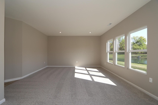 carpeted spare room with a water view