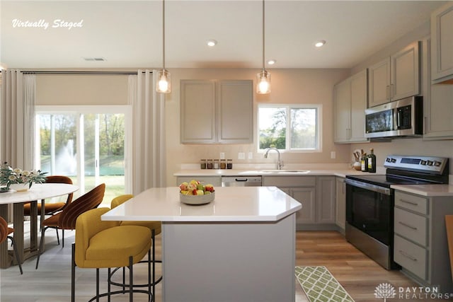 kitchen with sink, light hardwood / wood-style floors, decorative light fixtures, and appliances with stainless steel finishes