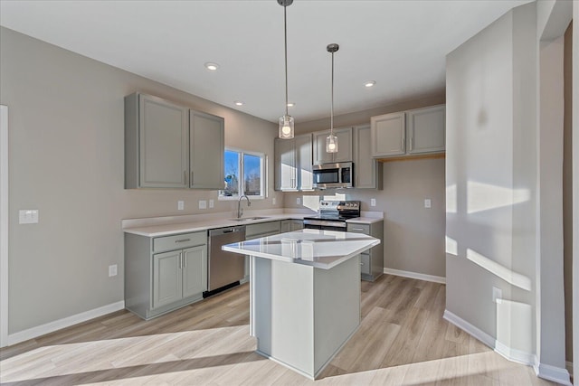 kitchen featuring a center island, sink, light wood-type flooring, decorative light fixtures, and stainless steel appliances