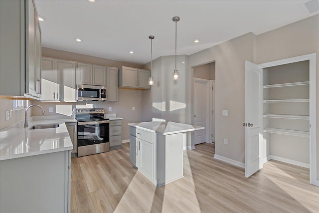 kitchen featuring light wood-type flooring, gray cabinetry, stainless steel appliances, sink, and a kitchen island