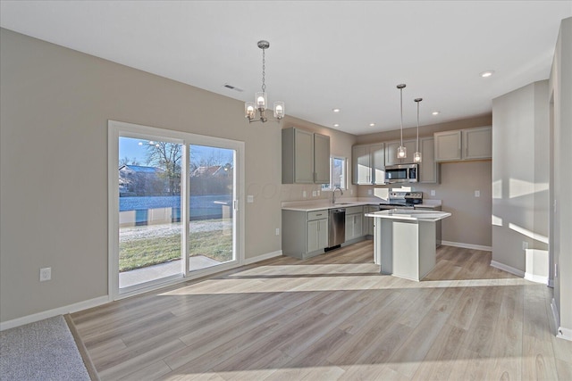 kitchen featuring gray cabinetry, a kitchen island, hanging light fixtures, and appliances with stainless steel finishes