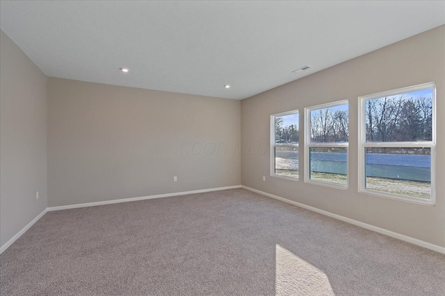 unfurnished room with carpet and a water view