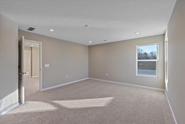 spare room with a textured ceiling and light carpet