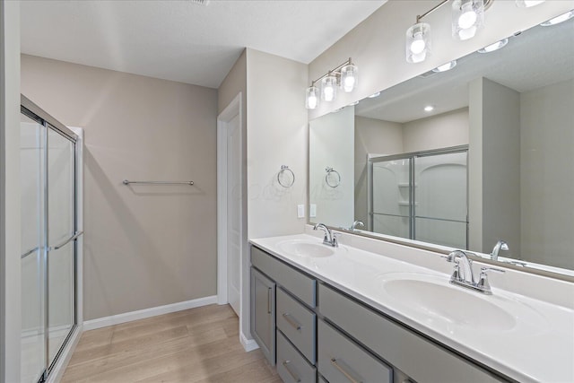 bathroom featuring hardwood / wood-style floors, vanity, and a shower with shower door