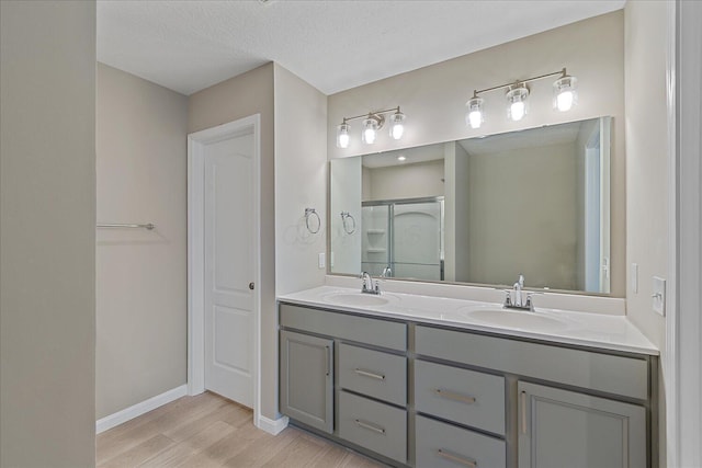 bathroom with vanity, wood-type flooring, a textured ceiling, and a shower with door