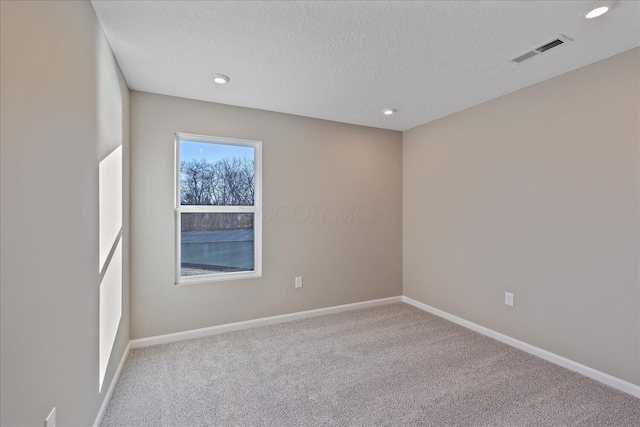 carpeted spare room with a textured ceiling