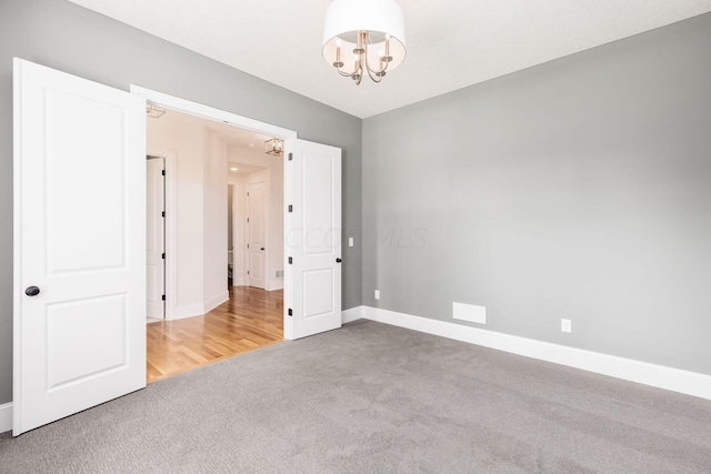 carpeted spare room with a notable chandelier