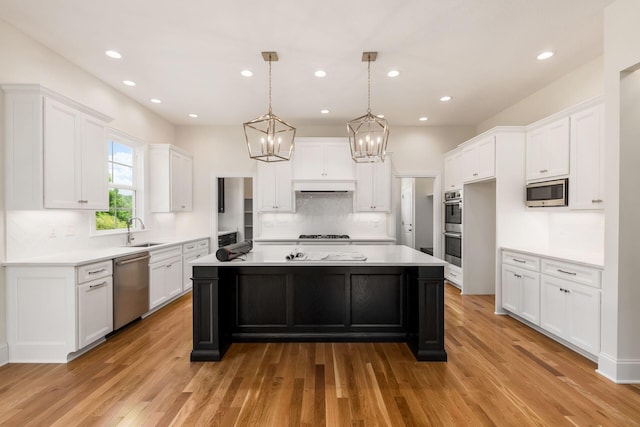 kitchen featuring appliances with stainless steel finishes, a kitchen island, sink, light hardwood / wood-style flooring, and white cabinetry