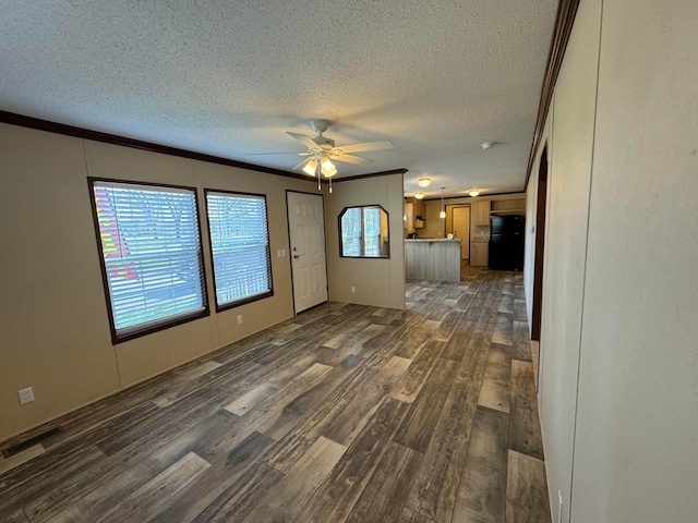 unfurnished living room featuring a textured ceiling, dark hardwood / wood-style floors, ceiling fan, and crown molding