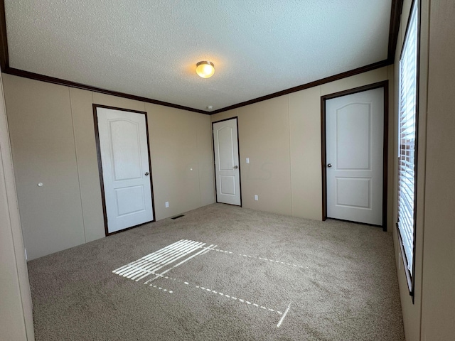 unfurnished bedroom with carpet flooring, crown molding, and a textured ceiling