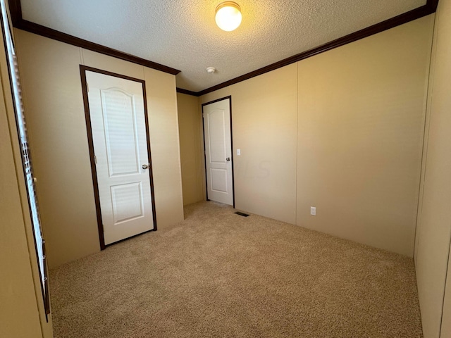 unfurnished bedroom featuring light carpet, a textured ceiling, and crown molding