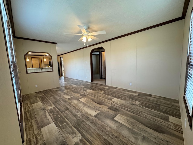 spare room featuring a textured ceiling, ceiling fan, crown molding, and dark wood-type flooring