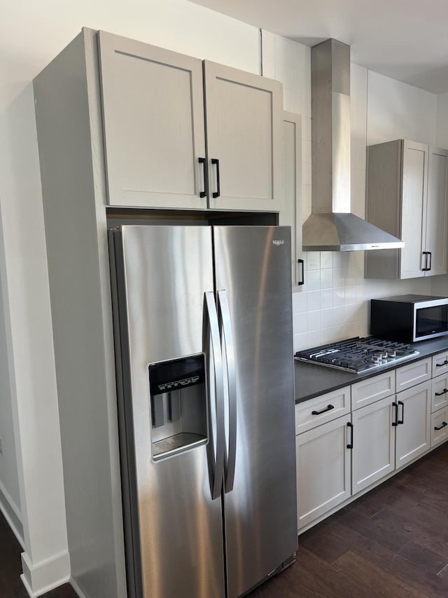 kitchen featuring wall chimney exhaust hood, dark hardwood / wood-style flooring, backsplash, and appliances with stainless steel finishes