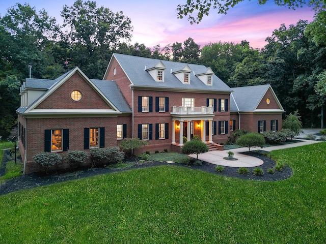 colonial home featuring a balcony and a yard