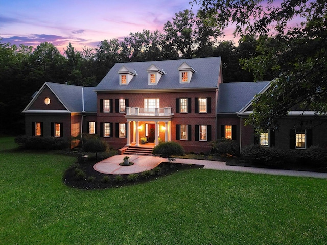 view of front of house featuring a lawn and a balcony