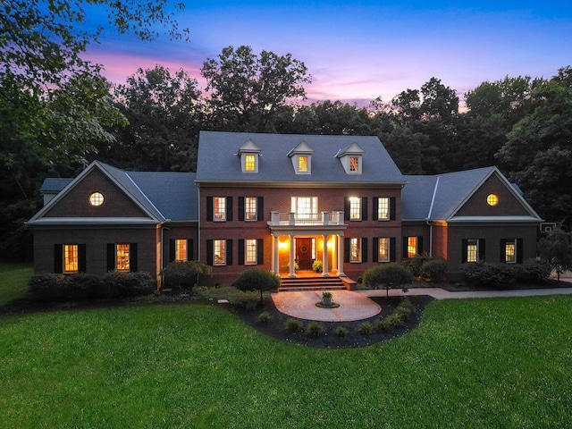 view of front of house with a lawn and a balcony