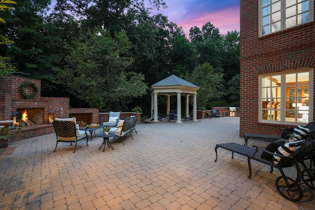 patio terrace at dusk featuring a gazebo and an outdoor living space with a fireplace