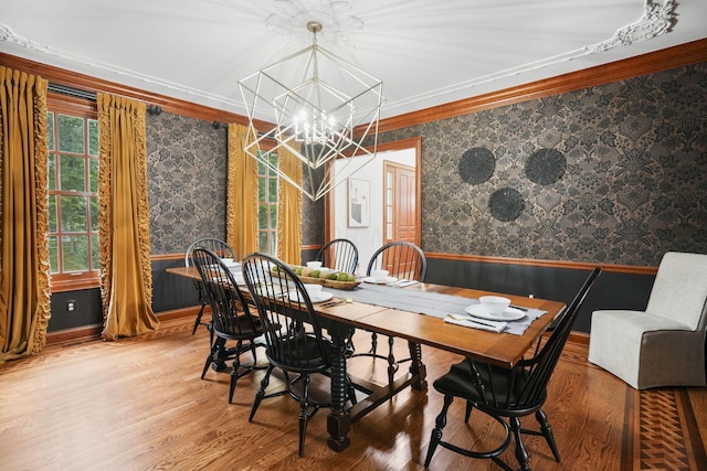 dining area with crown molding, wood-type flooring, and an inviting chandelier