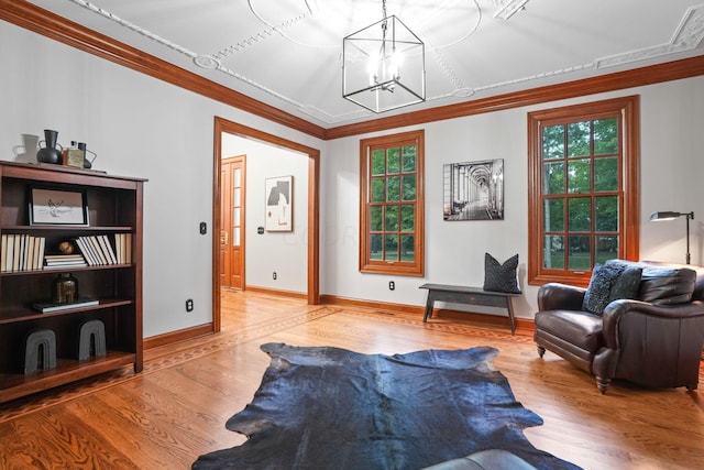 sitting room with a chandelier, light wood-type flooring, and crown molding