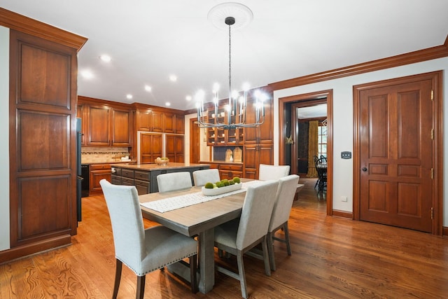 dining space featuring hardwood / wood-style floors, ornamental molding, and a notable chandelier