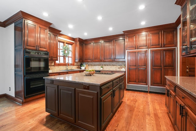 kitchen featuring sink, a center island, tasteful backsplash, light hardwood / wood-style flooring, and double oven