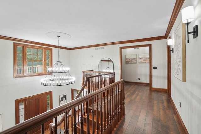 corridor featuring crown molding, dark wood-type flooring, and an inviting chandelier