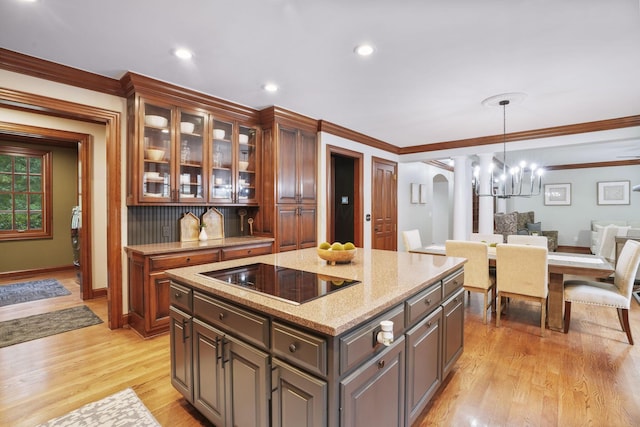 kitchen featuring black electric stovetop, dark brown cabinets, crown molding, light hardwood / wood-style flooring, and a kitchen island