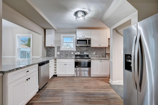 1468 E Whittier St, Columbus, OH 43206 - kitchen featuring stainless steel appliances, white cabinetry, tasteful backsplash, light stone counters, and light wood-type flooring