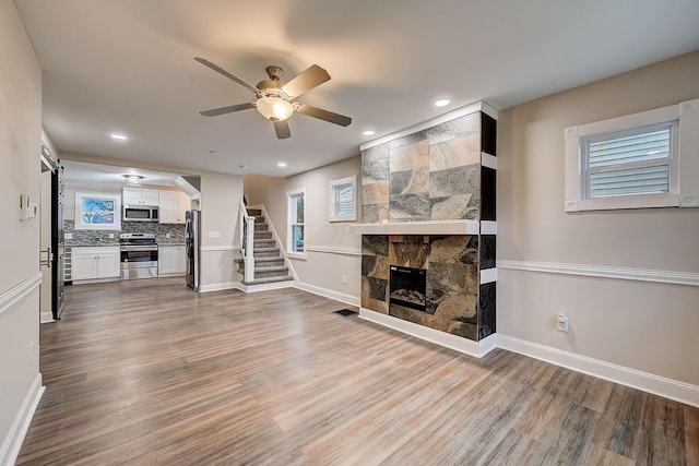 1468 E Whittier St, Columbus, OH 43206 - unfurnished living room with ceiling fan, stairway, a fireplace, wood finished floors, and recessed lighting