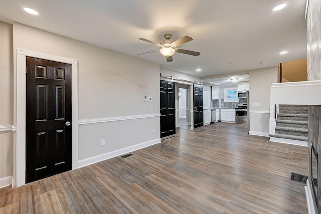 1468 E Whittier St, Columbus, OH 43206 - unfurnished living room featuring a barn door, a ceiling fan, stairs, dark wood-type flooring, and recessed lighting