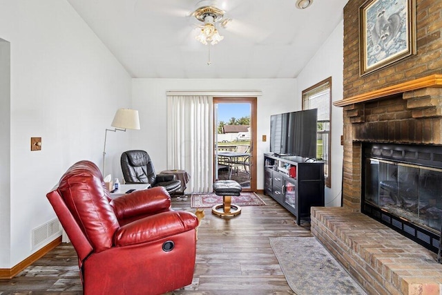 living room with dark hardwood / wood-style floors, ceiling fan, lofted ceiling, and a brick fireplace