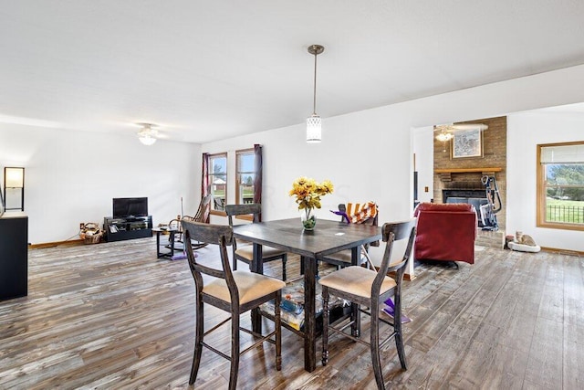 dining area with a fireplace, wood-type flooring, and a healthy amount of sunlight