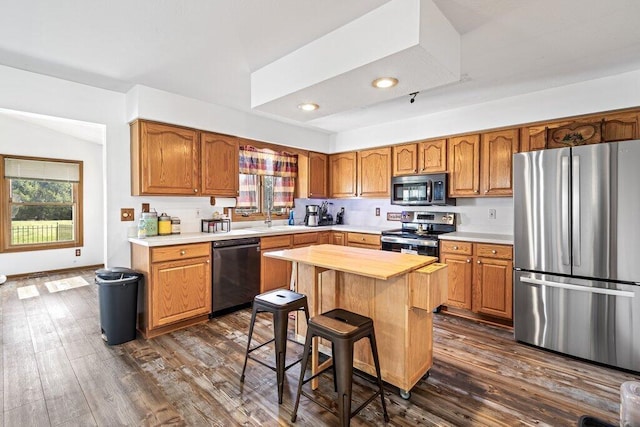 kitchen with wood counters, a center island, dark wood-type flooring, sink, and appliances with stainless steel finishes