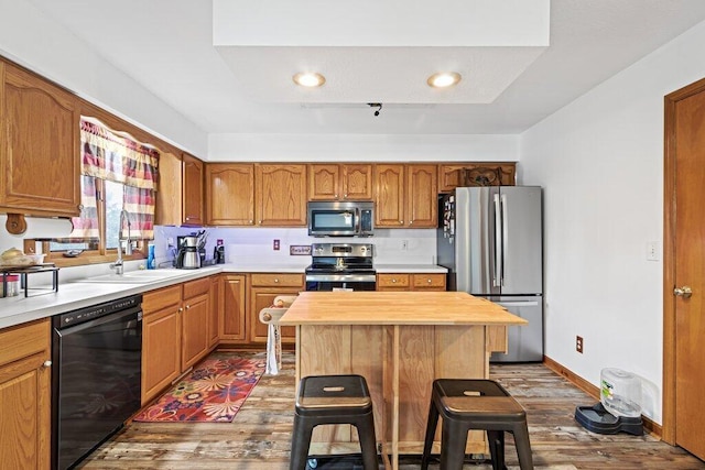 kitchen with appliances with stainless steel finishes, dark wood-type flooring, sink, butcher block countertops, and a kitchen island