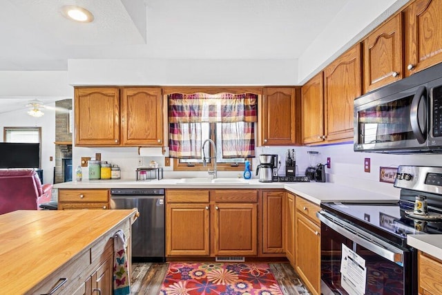 kitchen with wood counters, appliances with stainless steel finishes, dark hardwood / wood-style flooring, ceiling fan, and sink