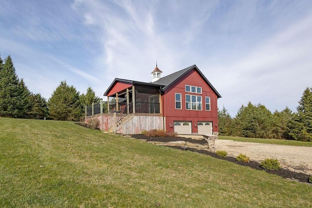 rear view of property featuring a sunroom, a garage, and a yard