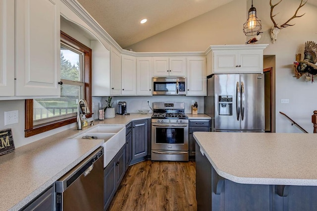 kitchen with decorative light fixtures, white cabinetry, stainless steel appliances, and vaulted ceiling