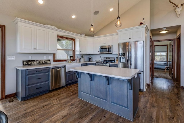 kitchen featuring pendant lighting, white cabinets, stainless steel appliances, and a kitchen island