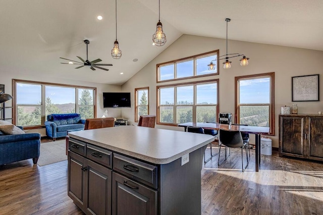 kitchen with ceiling fan, a kitchen island, hanging light fixtures, and dark hardwood / wood-style floors