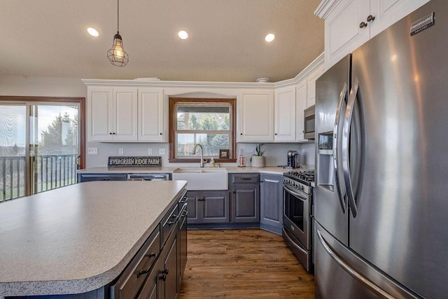 kitchen featuring sink, white cabinets, stainless steel appliances, and decorative light fixtures