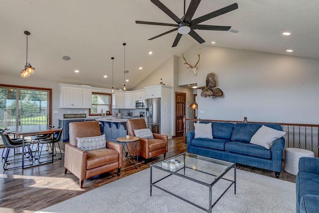 living room with ceiling fan, high vaulted ceiling, and light hardwood / wood-style flooring