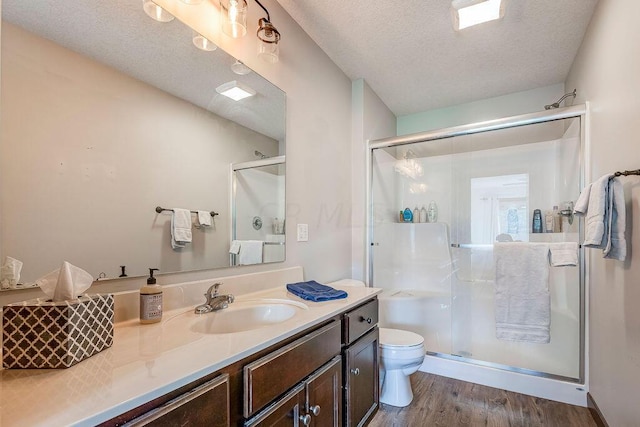 bathroom featuring hardwood / wood-style floors, a shower with shower door, a textured ceiling, and toilet