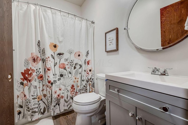 bathroom featuring wood-type flooring, vanity, toilet, and walk in shower