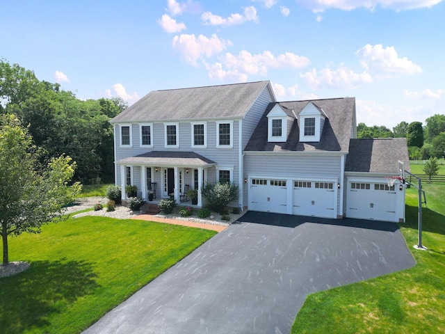 view of front of home with a front yard, covered porch, and a garage