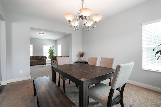 dining area with carpet and a notable chandelier