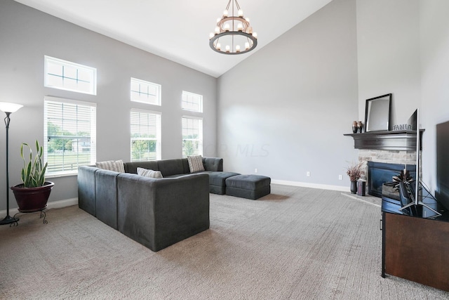 carpeted living room with high vaulted ceiling, a stone fireplace, and a notable chandelier