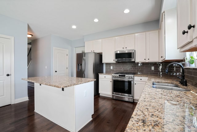 kitchen with a kitchen island, sink, appliances with stainless steel finishes, a breakfast bar area, and light stone counters