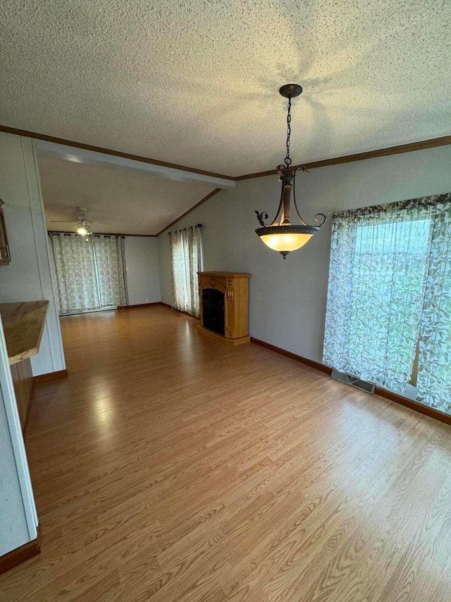 unfurnished dining area featuring wood-type flooring, a textured ceiling, crown molding, and beam ceiling